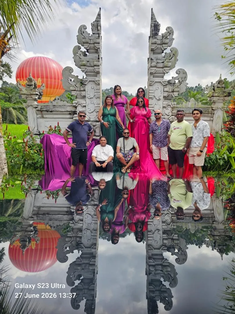 Reflection of travellers in colourful gowns standing beneath the Gates of Heaven at Lempuyang Temple, Bali